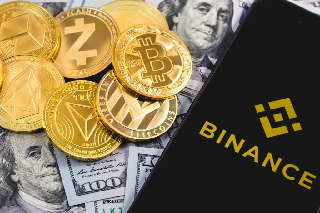 Phone with an open Binance app next to different crypto coins